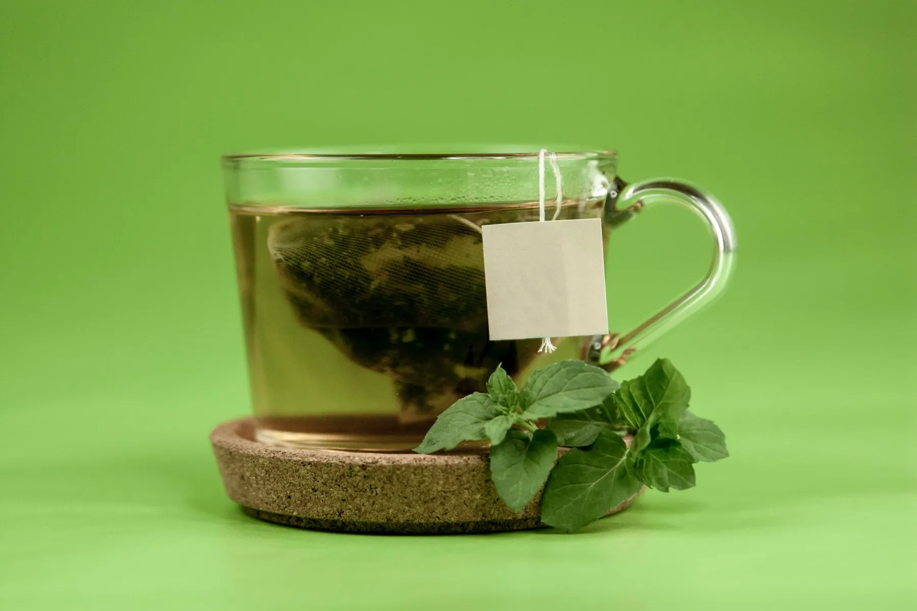 A transparent cup of freshly brewed green tea with mint.