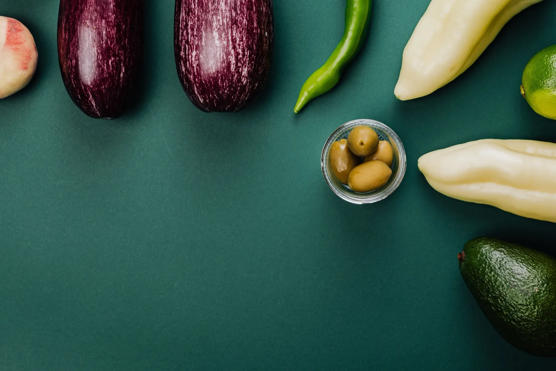 A variety of fresh fruits and vegetables arranged on a dark cyan surface.