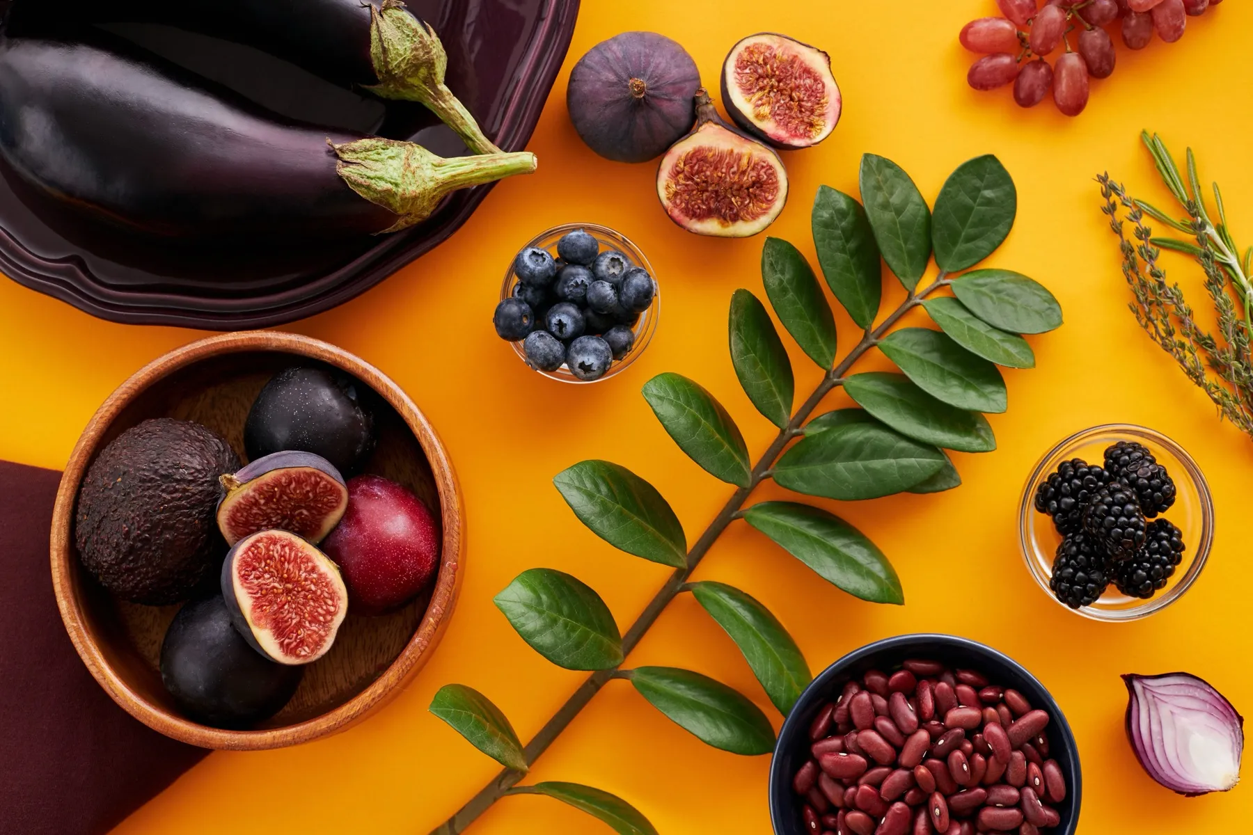 Fresh leaves among fruits and vegetables arranged on a warm surface.